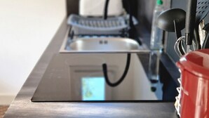 A kitchen counter with a stainless steel sink, a red pot, and various kitchen utensils. - Appartement "2" Villa Cây Tre Classé 3* (Rochefort)