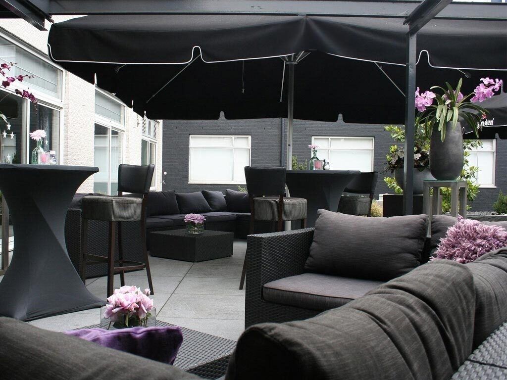 Un área de patio al aire libre con una paleta moderna de colores negro y gris, que incluye un sofá, sillas y una mesa.