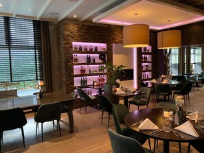 A restaurant with wooden floors, black chairs, and a bar area with shelves of bottles. - Your Gateway to Fun & Relaxation: A Hidden Gem in Nature Near Beekse Bergen Zoo (Waalwijk)