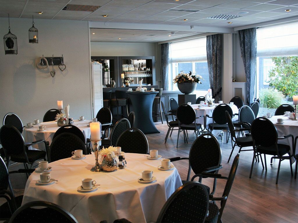 A dining area with round tables, chairs, and a bar in the background.