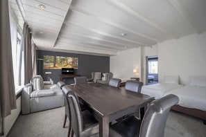 A hotel room with a large wooden table, multiple seating options, a bed, and a television. - Rest & Recharge: Scenic Retreat Near Loonse and Drunense Duinen National Park (Waalwijk)