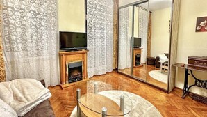 A living room with a glass coffee table, a sofa, a fireplace, and a television. - Charming studio with balcony near Ostrów Tumski Cathedral Island - Old Town in 15 min (Breslau)