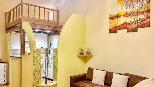 A living room with a brown sofa, a glass coffee table, and a painting on the wall. - Charming studio with balcony near Ostrów Tumski Cathedral Island - Old Town in 15 min (Breslau)