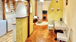 A cozy living room with a herringbone floor, a fireplace, a television, and a dining area with a table and chairs. - Charming studio with balcony near Ostrów Tumski Cathedral Island - Old Town in 15 min (Breslau)