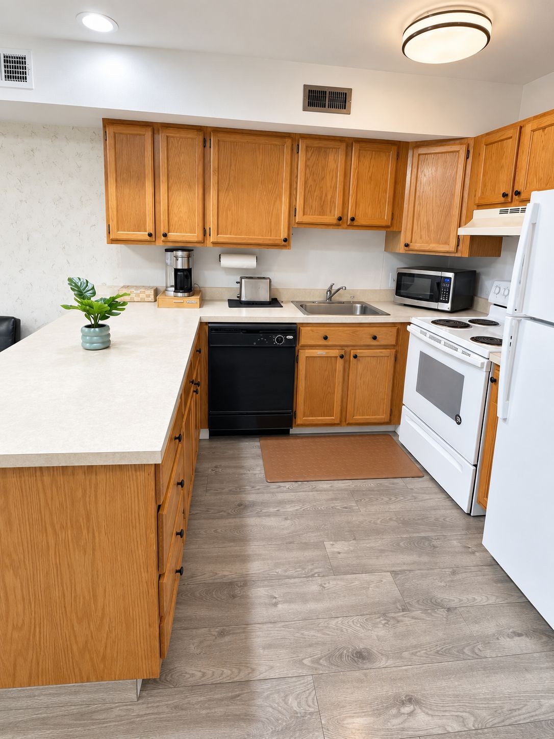 A modern kitchen with wooden cabinets, a dishwasher, a microwave, a stove, and a sink.