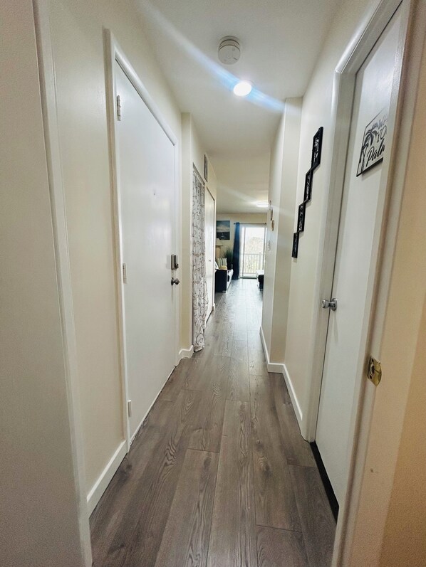 A hallway with wooden flooring, white walls, and doors leading to other rooms. - Bayside Beauty- Walk to the Beach
Cozy 1-bedroom condo in charming Ocean City (Ocean City)
