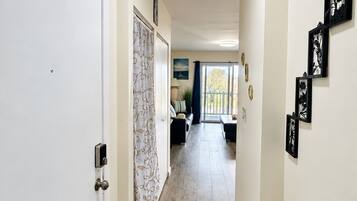 A hallway with a white door, a patterned curtain, and a view to a balcony.
