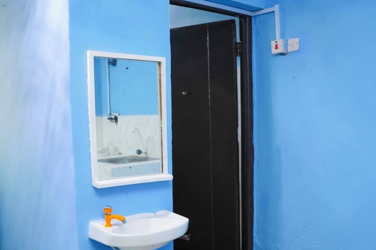 Un baño con un lavabo blanco, un espejo y una puerta negra.