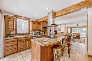 A spacious kitchen with wooden cabinets, a large island with bar stools, and a view to the living area. - Park City Family Retreat Hot Tub Pet Friendly 177 3 Bedroom Condo (Park City)