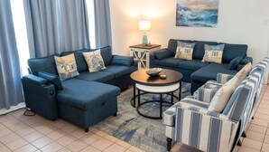 A living room with two sofas, a coffee table, and striped armchairs. - Walkable Location 99 Steps To Beach Pool 2 Bedroom Apts (South Padre Island)