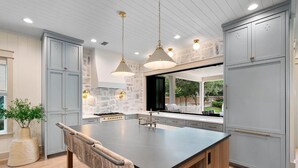 Une cuisine moderne avec des meubles gris, un îlot central et des luminaires suspendus.