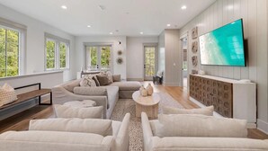 Un salon moderne avec un canapé d’angle, une table basse et un téléviseur à écran plat fixé au mur.