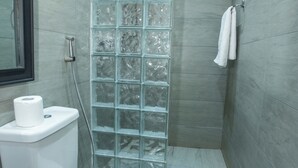 Un bany modern amb una dutxa de vidre, un vàter i un lavabo.