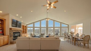 A spacious living room with a large sectional sofa, a fireplace, and a dining area with wooden chairs and a table. - Grand View at Innsbrook by Innsbrook Vacations! (Innsbrook)