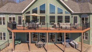 A green house with a covered patio, outdoor seating, and large windows. - Grand View at Innsbrook by Innsbrook Vacations! (Innsbrook)