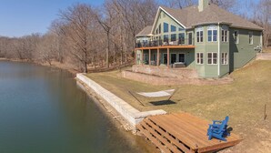 A large house with a balcony overlooking a body of water, a dock, and a grassy area. - Grand View at Innsbrook by Innsbrook Vacations! (Innsbrook)