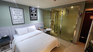 A hotel room with a bed, a chair, a small table, and a walk-in closet. - Sixty Motel (Seoul)