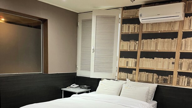 Camera da letto moderna con un letto grande, un comodino, un condizionatore d'aria a parete e una libreria.