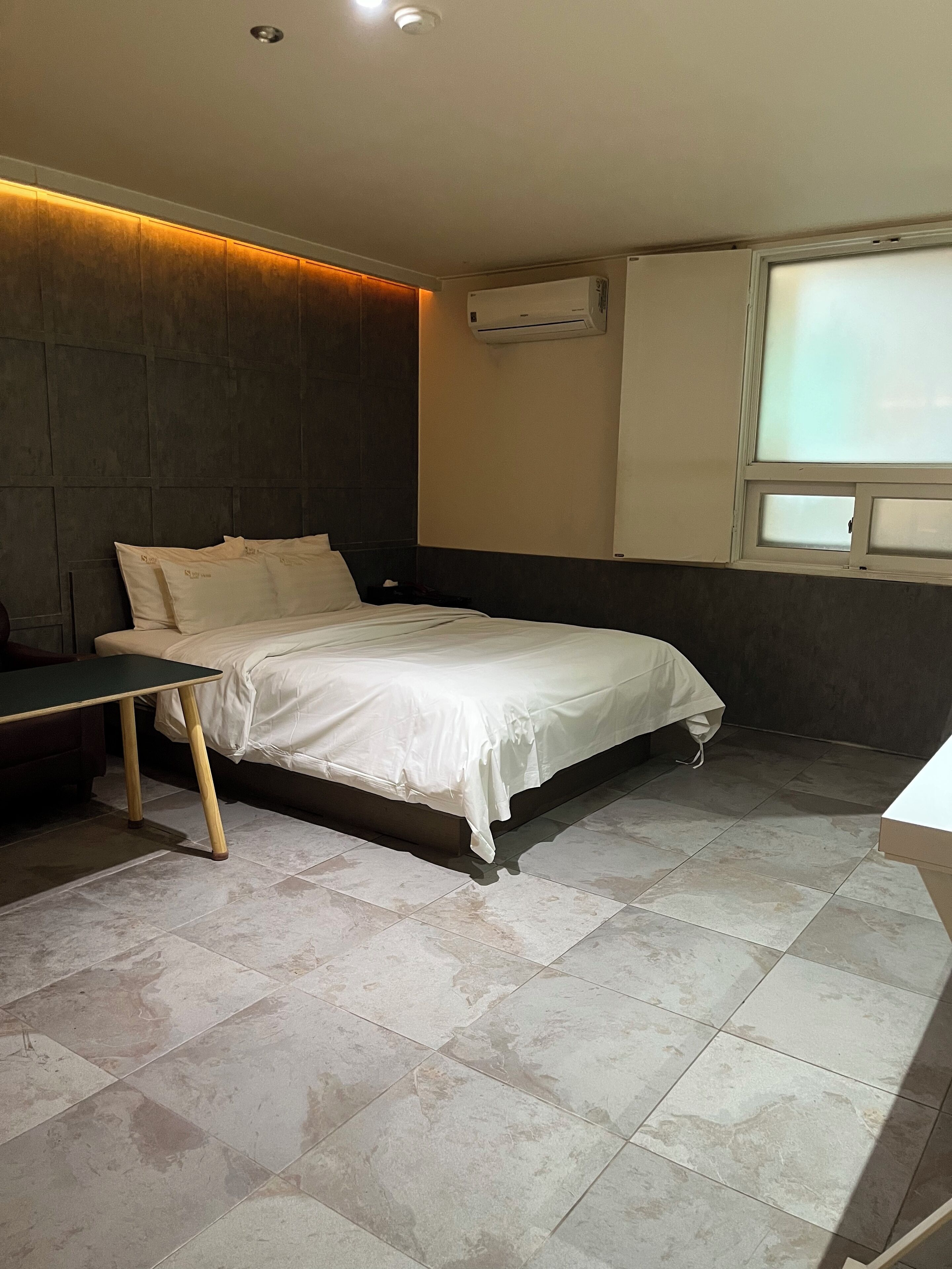 Un dormitorio moderno con cama, escritorio y equipo de aire acondicionado.