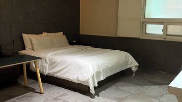 Un dormitorio moderno con cama, escritorio y equipo de aire acondicionado.
