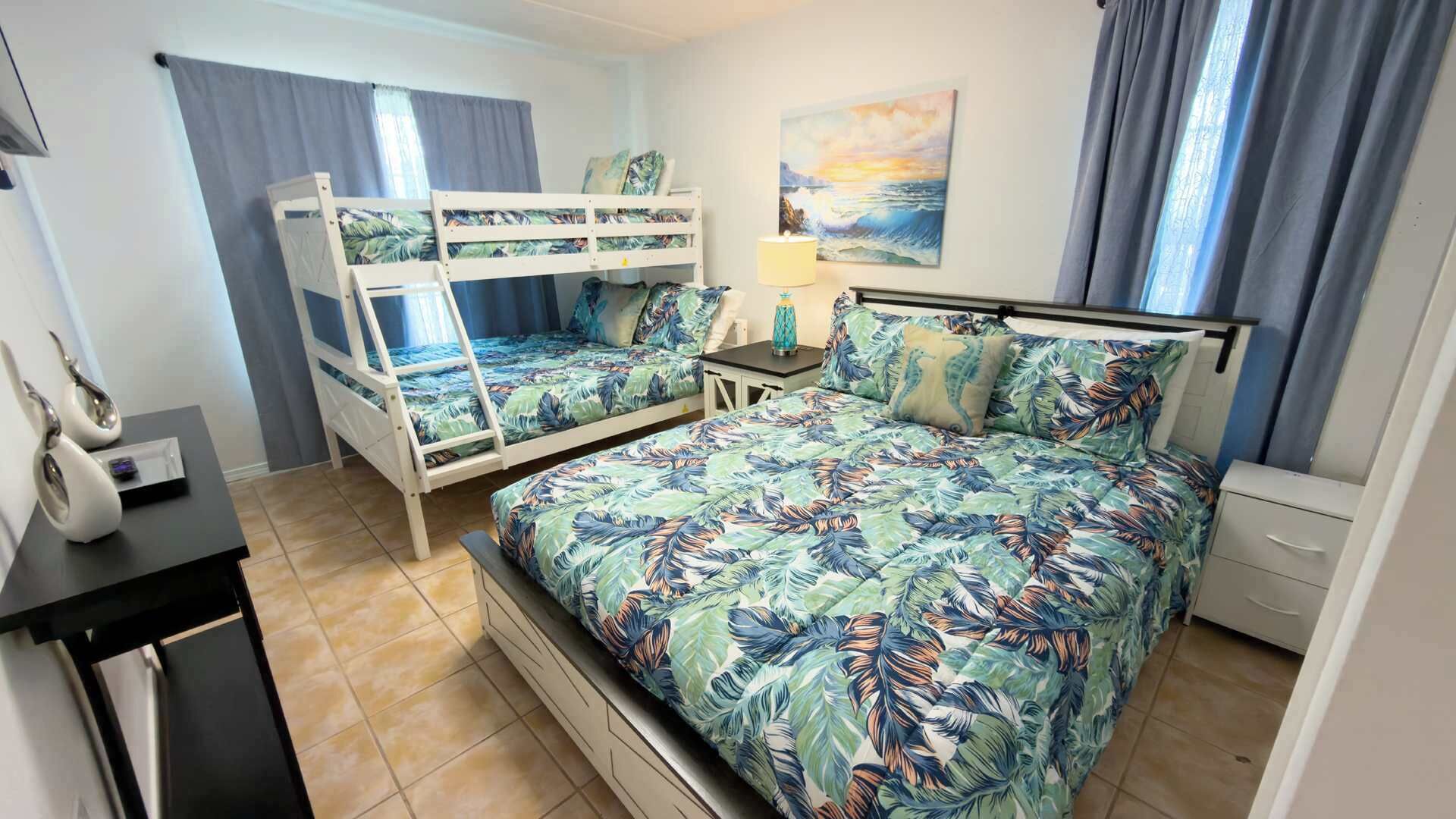 A room with bunk beds, a desk, a lamp, and a painting on the wall.