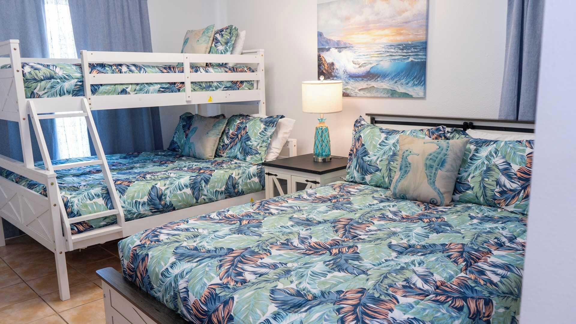 A room with bunk beds, a small table with a lamp, and a painting of a seascape.