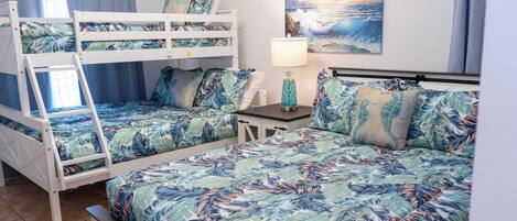 A room with bunk beds, a small table with a lamp, and a painting of a seascape.