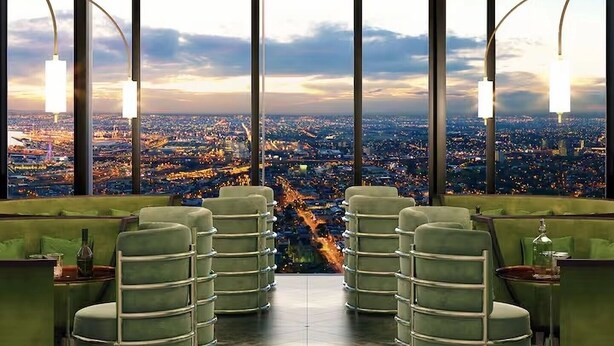 Eine moderne Bar mit Panoramablick auf die Stadt, ausgestattet mit hohen Decken und grünen Sitzgelegenheiten.