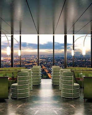 Um bar moderno com vista panorâmica da cidade, com tetos altos e assentos verdes.