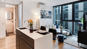 Eine moderne Küche mit einer zentralen Kochinsel, einem Essbereich mit rundem Tisch und einem großen Fenster mit Blick auf die Stadtlandschaft.