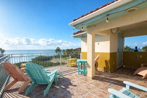 A balcony with chairs and a table, overlooking a coastal view. - Sunset Bay Views-Private 3 Levels-Rooftop Deck (South Padre Island)
