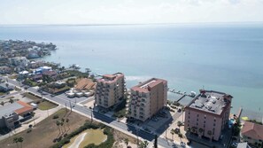 A coastal residential area with multi-story buildings, a marina, and a clear view of the ocean. - Direct Bayfront Sunsets - Boat Docks - Pool - Fish (South Padre Island)
