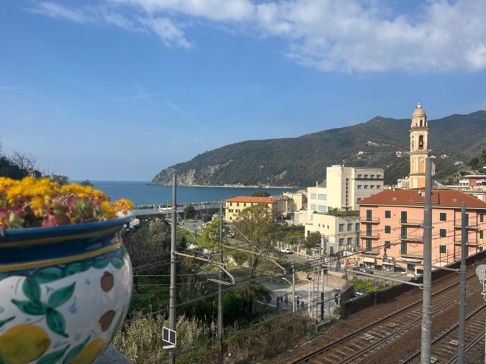 A coastal town with a prominent clock tower, railway tracks, and a view of the sea.