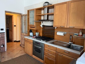 A compact kitchen with wooden cabinets, a built-in oven, a gas stove, and a stainless steel sink. - Km 54 – 1,200 m from the sea. Free parking. Expenses included. (Moneglia)