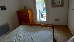 A bedroom with a wooden bed, a dresser, a mirror, and a window with curtains. - Cap d'Agde, Garden level Res. Agathe Plus, near Roquille and Mole beaches (Agde)