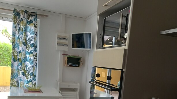 A modern kitchen with white cabinets, a built-in oven, and a small refrigerator. - Cap d'Agde, Garden level Res. Agathe Plus, near Roquille and Mole beaches (Agde)