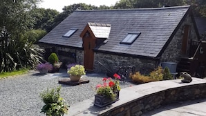 A stone building with a sloped roof, two skylights, and a gravel driveway. - A Beautiful Cottage in the Snowdonia National Park (Tywyn)