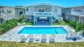 A two-story house with a pool, outdoor seating, and a fenced yard. - 318 Underwood Drive (South Wind 2.0)- Three Bedroom Home with a Private Pool! (Garden City Beach)