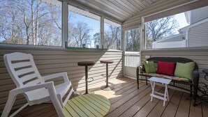 A covered porch with a white chair, a small round table, and a wicker sofa with cushions. - Bright and Airy Townhouse in Reserves of Nassau - 17316 King Philip Way (Lewes)