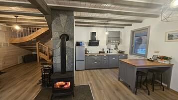A modern kitchen with a central island, a built-in stove, and a wooden staircase.
