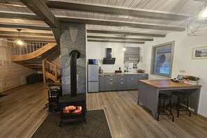 Una cocina moderna con una isla central, estufa integrada y una escalera de madera.