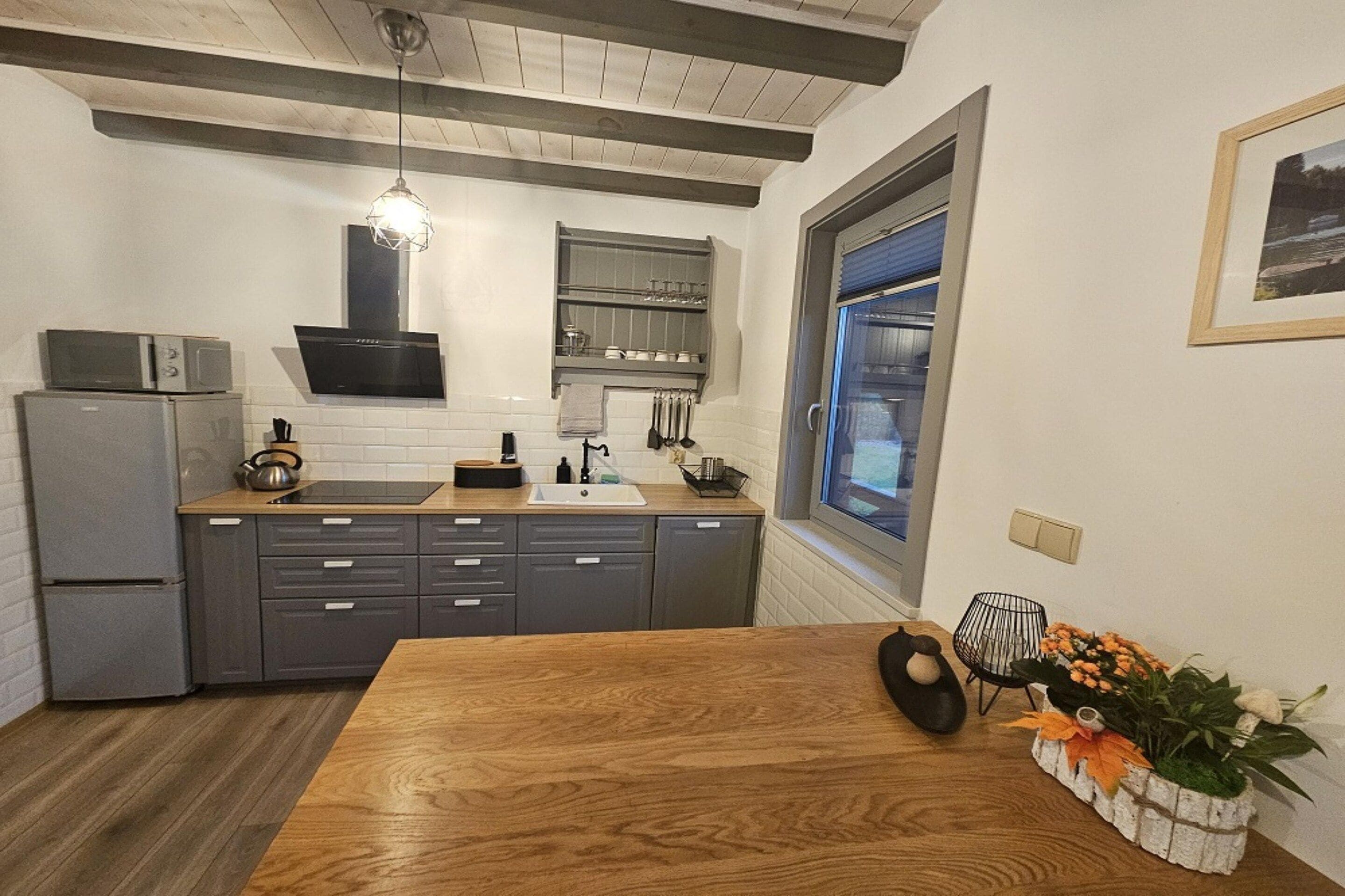 A modern kitchen with a wooden table, grey cabinets, and a built-in oven.