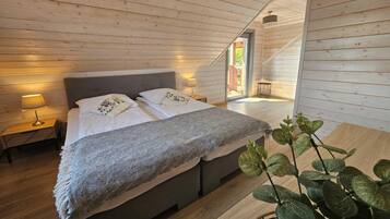 Quarto com cama, luminárias de cabeceira, janela e escada para um andar superior.