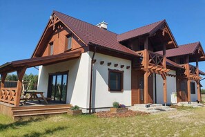 A two-story house with a wooden exterior, large windows, and a covered porch. - Comfortable Holiday Home With a Terrace and Garden (Karsin)