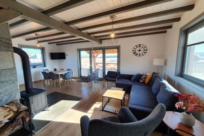 A spacious living area with a fireplace, a sofa, a dining table, and a large window offering a view. - Comfortable Holiday Home With a Terrace and Garden (Karsin)