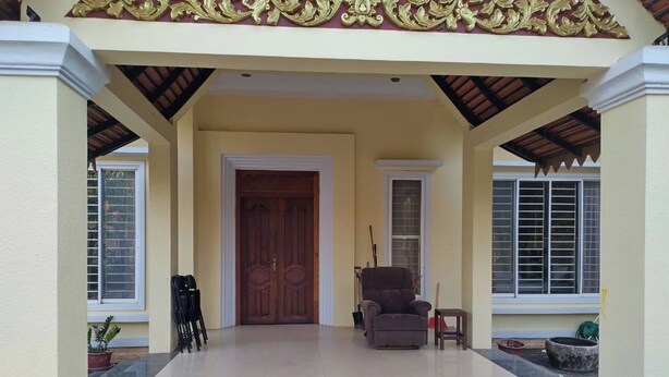 Un acceso cubierto con puerta de madera, una zona de estar con una silla y un felpudo.