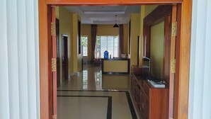 Un pasillo con mostrador de recepción, televisor y una ventana con cortinas.