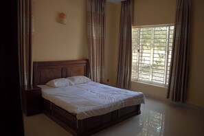 Ein Schlafzimmer mit einem hölzernen Bett, einem Nachttisch und einem Fenster mit Vorhängen.