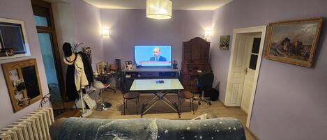 A living room with a television, a wooden cabinet, a desk, and a couch.