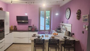 Une cuisine moderne avec un coin repas, comprenant un four encastré, un four à micro-ondes et une grande fenêtre.